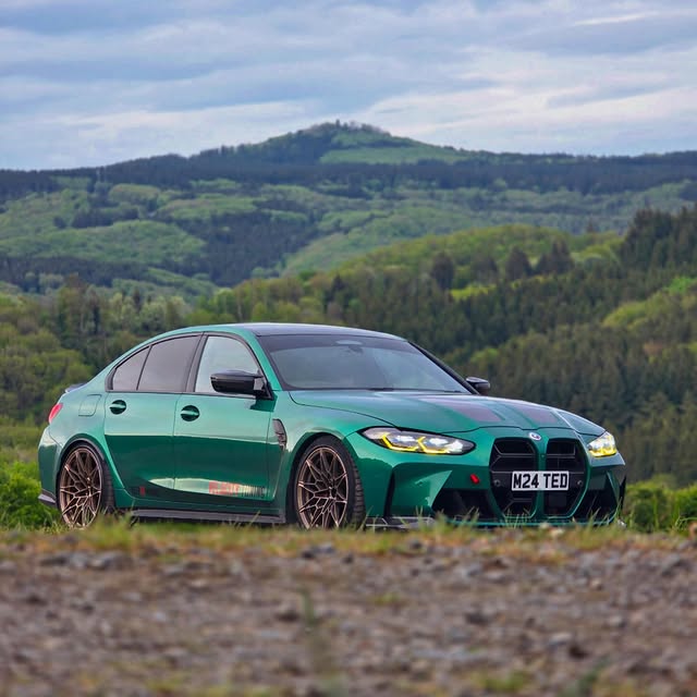 Green BMW M3 photographed against a wooded hillside
